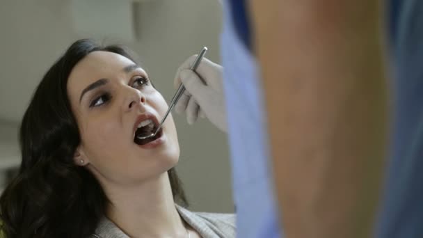 Dentista verifica os dentes de uma jovem mulher — Vídeo de Stock