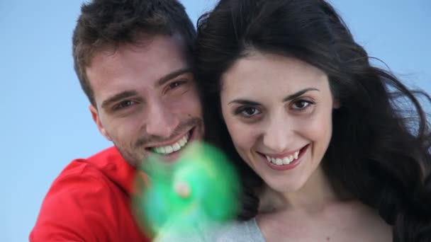 Feliz casal sorrindo brincando com um moinho de vento de brinquedo — Vídeo de Stock