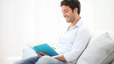 Adam kanepede oturan bir kitap okuma.