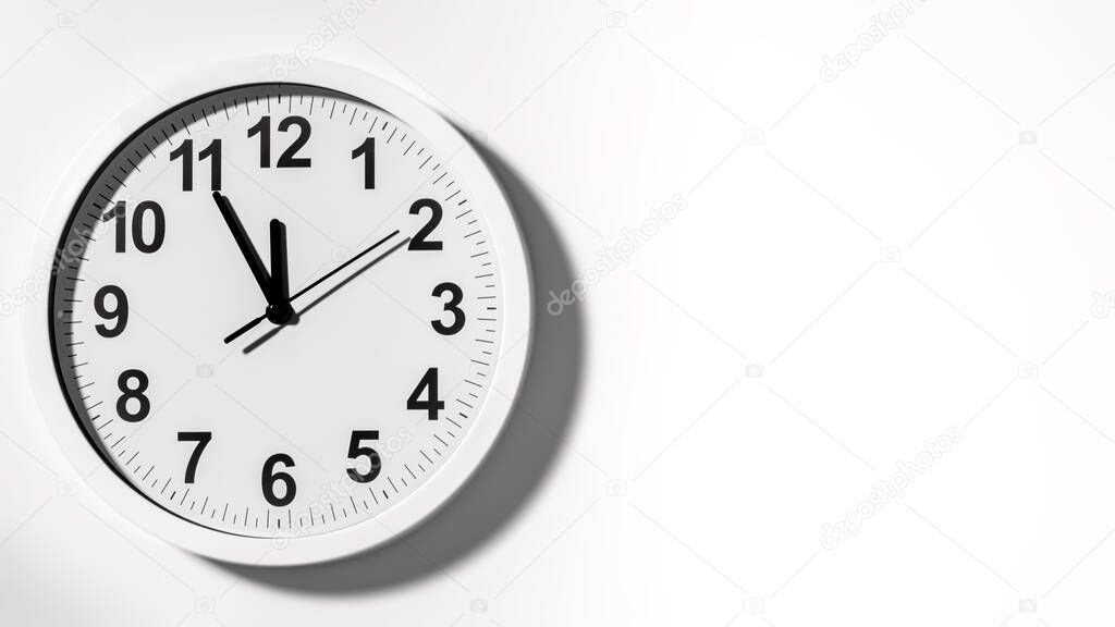 It is five to twelve, the clock is ticking. White Watch shows the time 5 before 12. Close up to a wall clock, with five minutes to twelve o'clock. Time is running out. White background with copy space