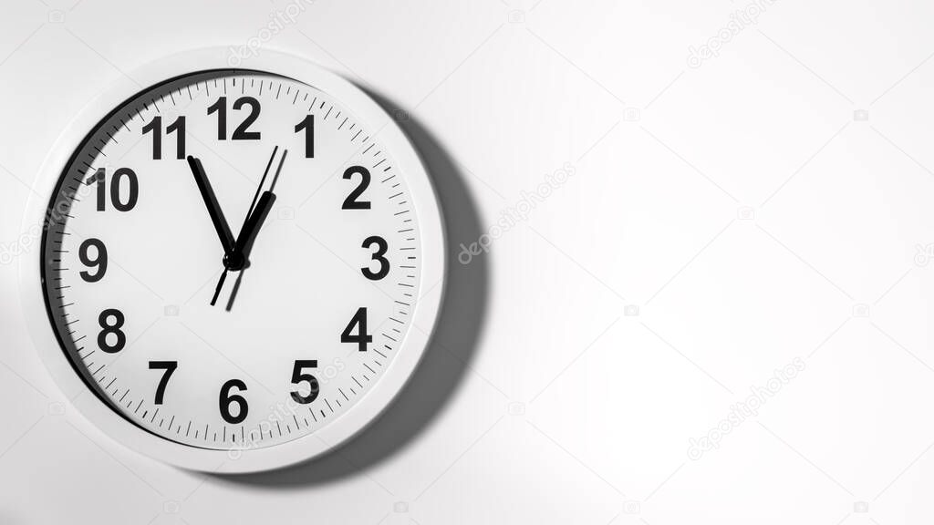 It is five to twelve, the clock is ticking. White Watch shows the time 5 before 12. Close up to a wall clock, with five minutes to twelve o'clock. Time is running out. White background with copy space