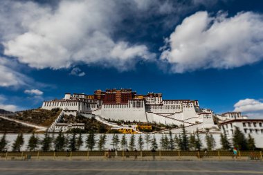 Lhasa, Tibet başkenti. Lhasa, Tibet, Çin 'deki Potala Sarayı. Chengguan 'da geniş açılı bir fotoğraf, yol kenarında dzong manzaralı. Mavi gökyüzünde beyaz bulutlar
