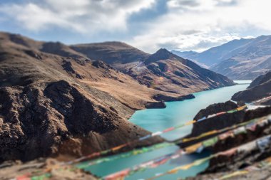 Kong mu Co Gölü, Tibet 'teki deniz seviyesinden 5000 metre yukarıda. Rüzgarda sallanan renkli dua bayrakları. Dağ gölünde turkuaz su. Eğim değişimi güçlü bir görsel efekt getirir