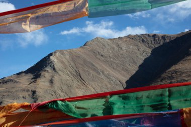 Himalaya dağlarının önünde bayraklar beliriyor. Tibet 'in muhteşem manzarası. Mavi gökyüzünün altında renkli bayraklar ve yüksek irtifada Tibet 'in Himalayalarında beyaz bulutlar.
