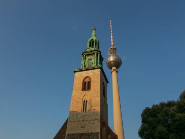 TV kulesi ve Almanya 'nın başkenti Berlin' deki St. Marien Kilisesi. Gün batımından önce Berlin 'de Fernsehturm ve St. Marienkirche. Kulenin tepesi batan güneşten altın olur.