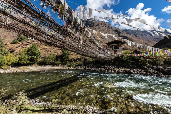 Bhutan Dağı manzarası, Paro-Thimphu otoyolunun yanındaki Paro Chu Nehri. Bhutanese Dağları 'nda renkli bayrakları olan bir dağ nehri üzerinde yürüyen asma köprü.. 