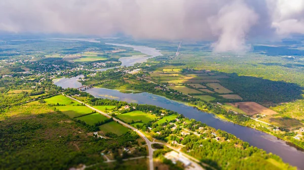 Aerial view over the Landscape of Canada, at Merrickville, Ontario, near the city of Ottawa. A River meanders through the green landscape under blue sky. Drone view, high above the clouds