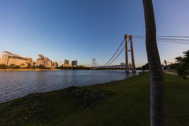 Putrajaya, Malezya 'da gün batımı. Mavi gökyüzü geceye düşüyor. Putrajaya 'daki gölde romantik bir atmosfer. Güneş batarken altın ışıkta tek raylı köprü. Putrajaya 'nın ufuk çizgisi. Şehir manzarası