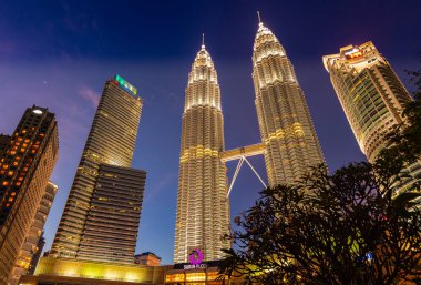 Kuala Lumpur, Malezya - 28 Kasım 2020: Petronas kulesinde gün batımı veya Güneydoğu Asya metropolünün merkezinde ikiz kuleler. Gece çöken Suria KL kuleleri. KLCC üzerinde renkli gökyüzü