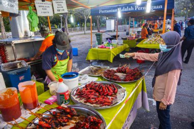 Kuala Lumpur, Malezya - 16 Ekim 2020: Putrajaya, Kuala Lumpur 'daki gece pazarında bal tavuk dükkanı. Müslüman bir Malay kadını parasını tezgahta öder. Yüz maskesi zorunludur.