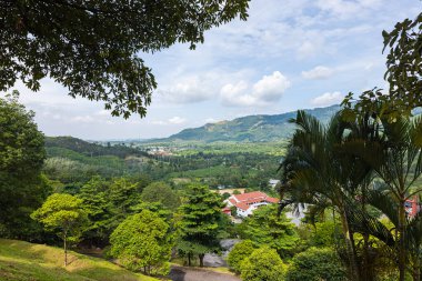Broga Hill Malezya yakınlarındaki bir vadiye bakın. Beyaz bulutlar ve mavi gökyüzü. Broga köyü ile vadiyi aşan orman ağaçlarının arasından bak. Arka planda Kuala Lumpur 'un ufuk çizgisi