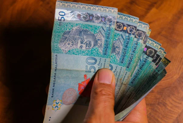 Elli Malezya halkalı banknot koleksiyonu bir erkeğin elinde. Malezya Ringgit banknotlarını göster. Erkekler Malezya 'nın parasını tutuyor. Asya parası. Ringgit notlarına yaklaş.  