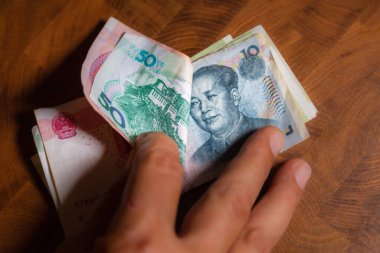 Erkek eli Renminbi 'yi veya Çin yuanını veya kısaca RMB banknotunu gösterir, Çin Halk Cumhuriyeti' nin resmi para birimidir. Ön tarafta Mao Zedong 'un portresi, Çin' in Kağıt Parası