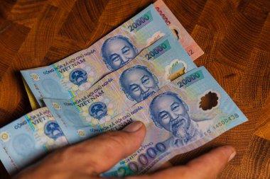 Vietnam 'ın para birimi olan Vietnamlı Dong banknotlarının hayranı bir erkek el. Vietnam 'ın Polimer Parası' nı kapatın. 20.000 Dong ya da VND, erkek eli. Ho Chi Minh 'in portresinin önünde. Plastik banknotlar