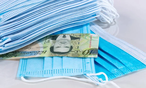 Beyaz arka planda yüz maskeleri ve Botswana Pula 'sı. Face yeni dünya para birimini maskeliyor. Corona virüsü ağız koruma için fiyatları yükseltti. Botswana parasına ve ağız korumasına yakın durun.