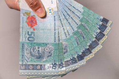 Elli Malezya halkalı banknot koleksiyonu bir kadının elinde. Kadın eli Malezya Ringgit banknotlarını gösteriyor. Malezya 'nın parasını tutan kızların elleri. Asya parası. Ringgit notlarına yaklaş.  