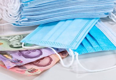 Yüz maskeleri, Tayland ve dünyanın en çok aranan ekipmanları. Corona Cov19 krizi yeni dünya para birimine ağız maskesi yapıyor. Fiyatlar yükseliyor. Beyaz arka planda Tayland bahtı. Tayland parası.. 