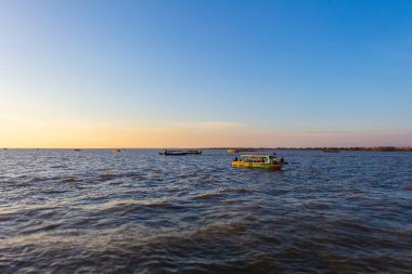 Tonle Sap Gölü 'nde gün batımı, Kamboçya, Kampong Phluk Yüzen Köyü ve Siem Reap yakınlarında. Renkli günbatımının tadını çıkarmak için turizm tekneleri denizde yüzüyor. Denizin üzerinde gün batımı ufku.