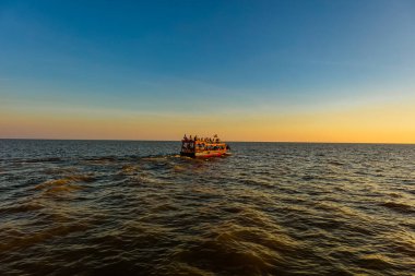 Tonle Sap Gölü 'nde gün batımı, Kamboçya, Kampong Phluk Yüzen Köyü ve Siem Reap yakınlarında. Renkli günbatımının tadını çıkarmak için turizm tekneleri denizde yüzüyor. Denizin üzerinde gün batımı ufku.