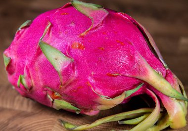 Olgun Pitaya 'nın ahşap arka planında kırmızı pembe bir ejderha meyvesine yaklaş. Tahta masada ejderha meyvesi.