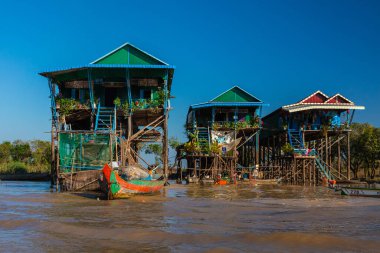 Gün batımında Kamboçya, Siem Reap yakınlarında Tonle Sap Gölü 'nde Kampong Phluk Yüzen Köyü. Yüzen kasabanın Stilt evleri. Güneydoğu Asya 'da egzotik yerler. Tekneler geziyor ve mal satıyor.