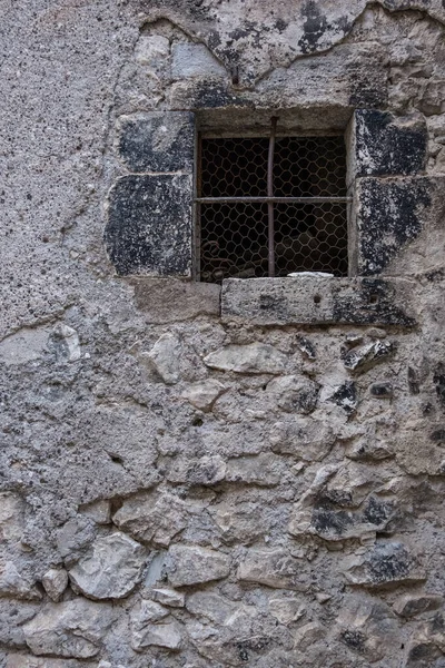 Old vintage window on an ancient facade. Medieval, stone and steel facade with rusty window. No people