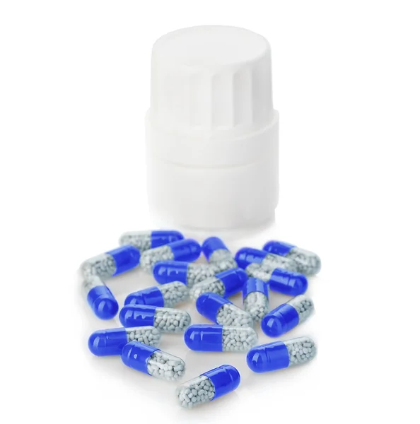 Blue capsules, pills poured out of a white bottle close-up on a white background. — Stock Photo, Image