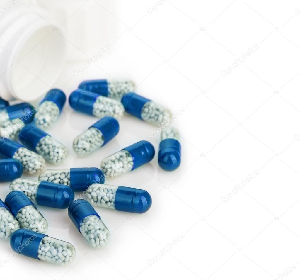 Blue capsules, pills poured out of a white bottle close-up on a white background.