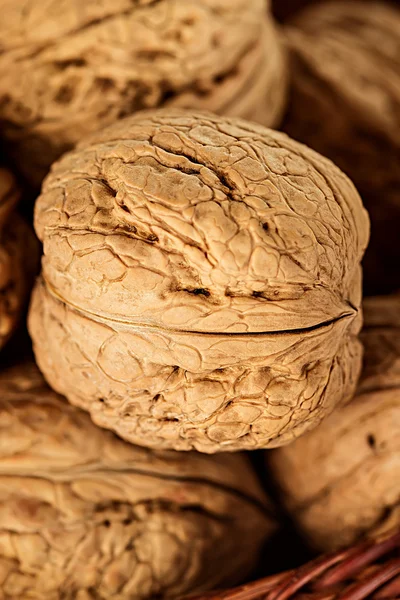 Целые грецкие орехи в плетеной корзине на деревенском, деревянном фоне — стоковое фото