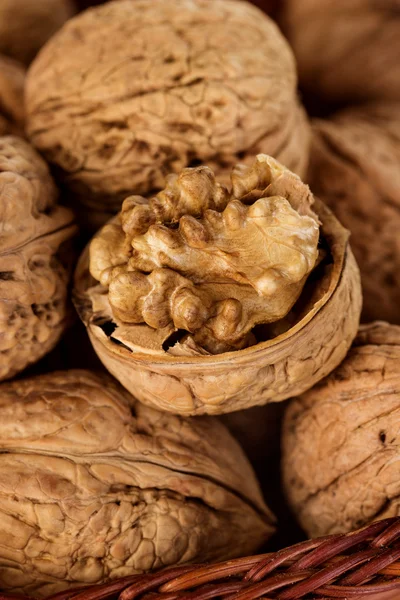 Целые грецкие орехи в плетеной корзине на деревенском, деревянном фоне — стоковое фото