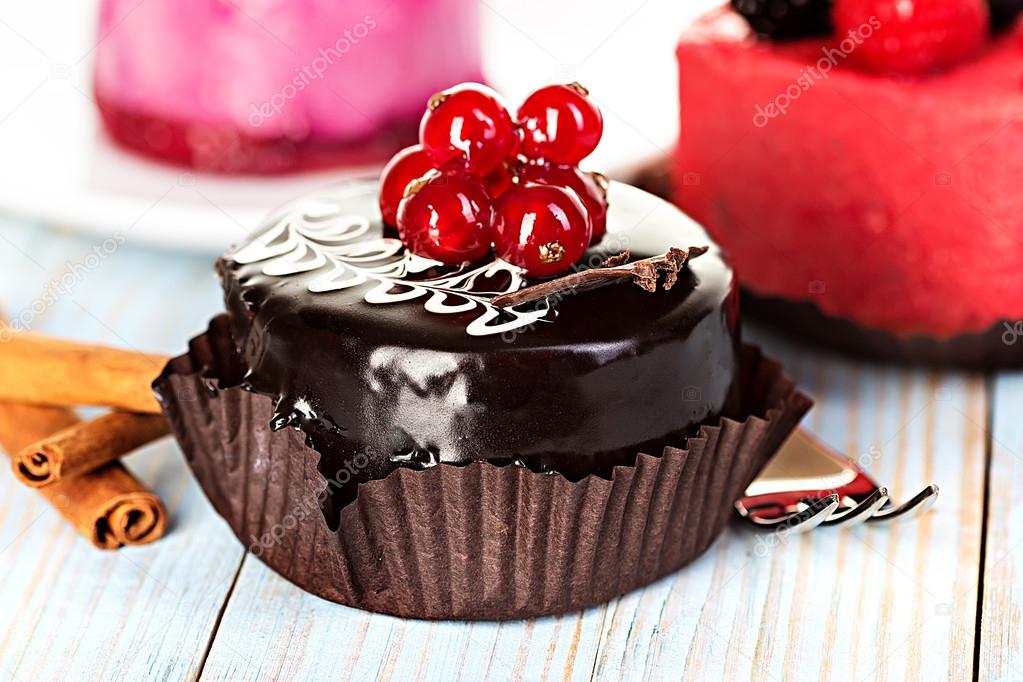 Chocolate cake with red currants on a wooden background