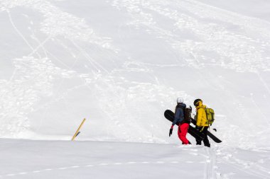 Tanımlanamayan genç snowboardcular karlı dağlarda yürüyorlar.