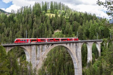 Davos Wiesen - 24 Haziran. 2021: Kırmızı bir yolcu treni Davos - Filisur, İsviçre Alplerindeki en yüksek viyadük olan Wiesener viyadük hattını geçiyor..