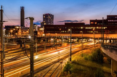 Gece Basel tren istasyonunda, giden trenler raylarda ışık yolları oluşturuyorlar.