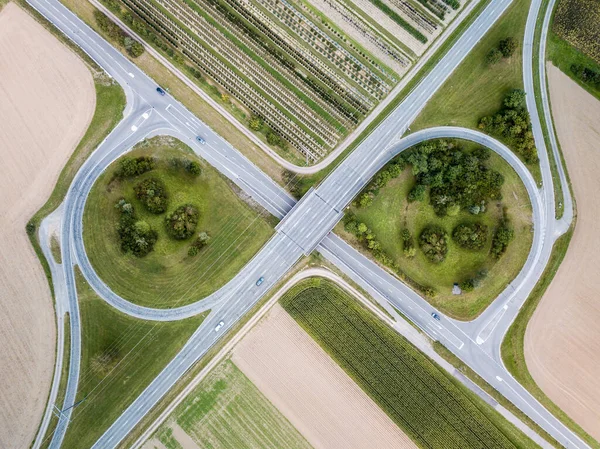 Aerial view of a symetric highway junction in the countryside with trees and cultivated fields. Bird\'s eye view.