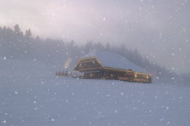 Emmental, İsviçre - 27 Kasım. 2025: Yalnız bir İsviçre geleneksel ahşap dağ evi güzel bir noel ışığı süslemesi ile kar alacakaranlıklarında