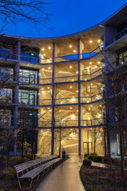 Allschwil, İsviçre - 08. Aralık 2025: Alacakaranlıkta İsviçre İnovasyon Parkı 'nın ticaret merkezinde merdivenleri açık olan ofisler, farklı şirket ve restoranlara ev sahipliği yapıyor..