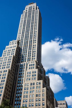 Manhattan 'da uzun bir gökdelen Parlak mavi bir gökyüzüne ve kabarık bulutlara karşı.