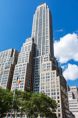 Manhattan 'da uzun bir gökdelen Parlak mavi bir gökyüzüne ve kabarık bulutlara karşı.