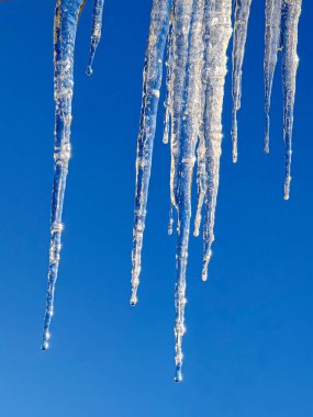 Mavi gökyüzüne karşı buz saçaklarına yakın çekim versiyonu.