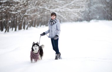 Kışın karlı ormanda Sibirya köpeğiyle gezen bir kız.