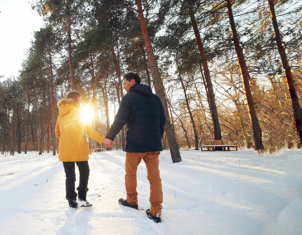 Casal jovem caminhando pela floresta de inverno segurando as mãos — Fotografia de Stock