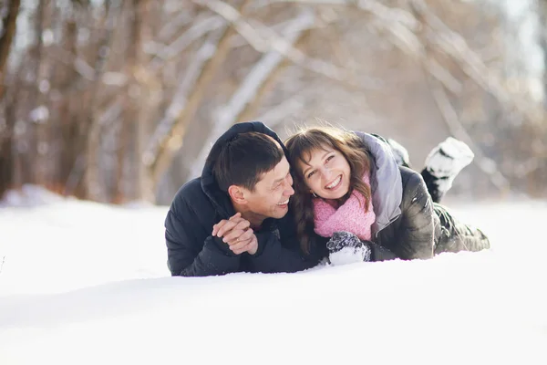 Casal feliz deitado na neve e rindo — Fotografia de Stock