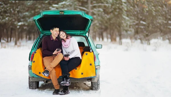 Glückliches Paar Das Winter Offenen Kofferraum Eines Autos Freien Sitzt lizenzfreie Stockfotos