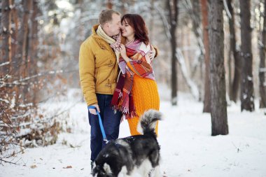Genç çift kışın köpekleriyle gülüyor ve parkta eğleniyorlar.