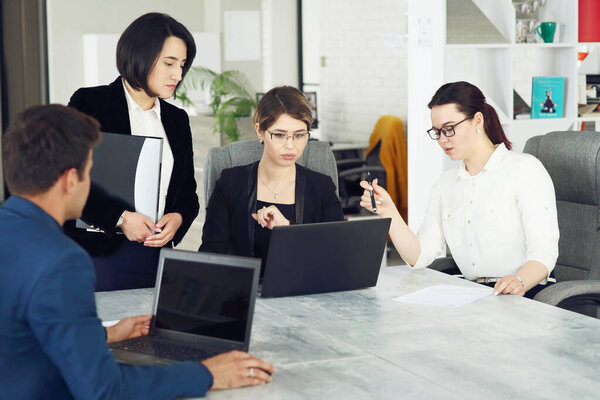 Three young successful business women in the office working together on a project. 