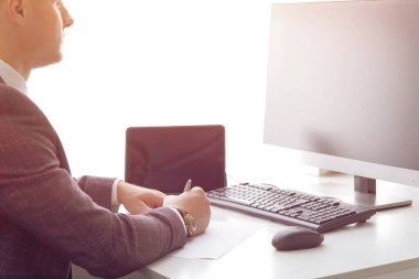 Bilgisayarda çalışan genç bir iş adamı ve masada kağıtlar.. 