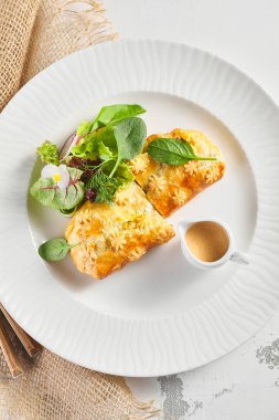 Karaciğer ve krema soslu turta. Taze yeşil yapraklarla süslenmiş. Çuval bezli beyaz tabak.