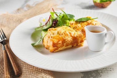 Karaciğer ve krema soslu turta. Taze yeşil yapraklarla süslenmiş. Çuval bezli beyaz tabak.