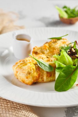 Karaciğer ve krema soslu turta. Taze yeşil yapraklarla süslenmiş. Çuval bezli beyaz tabak.